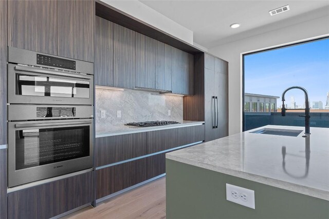 2209 S 1st St Unit 407, Austin, TX 78704 - kitchen featuring appliances with stainless steel finishes, backsplash, light wood finished floors, modern cabinets, and recessed lighting