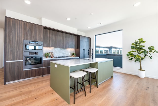 2209 S 1st St Unit 407, Austin, TX 78704 - kitchen featuring light countertops, modern cabinets, stainless steel appliances, a breakfast bar, and a center island with sink