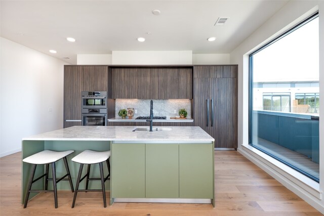 2209 S 1st St Unit 407, Austin, TX 78704 - kitchen with stainless steel appliances, modern cabinets, a kitchen island with sink, a breakfast bar, and tasteful backsplash