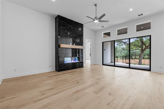 1304 Novara Trl, Leander, TX 78641 - unfurnished living room with a ceiling fan, a towering ceiling, a fireplace, wood finished floors, and recessed lighting