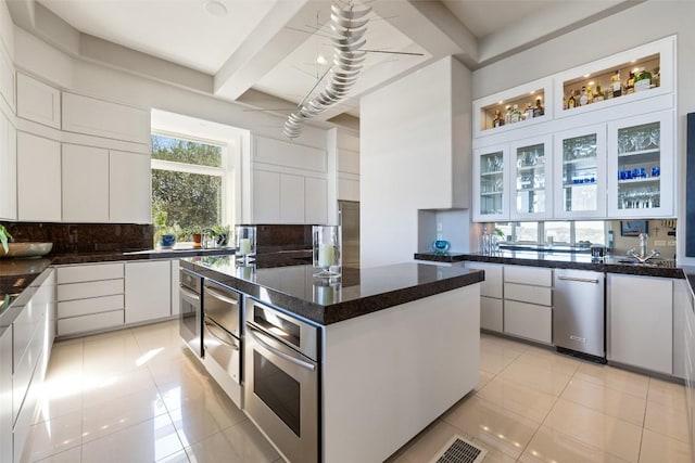715 Cutlass, Lakeway, TX 78734 - kitchen featuring stainless steel appliances, decorative backsplash, light tile patterned floors, white cabinetry, and beamed ceiling