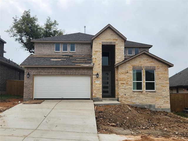 traditional home with an attached garage, stone siding, fence, concrete driveway, and roof with shingles