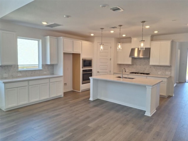 kitchen featuring visible vents, a sink, under cabinet range hood, white cabinetry, and stainless steel appliances