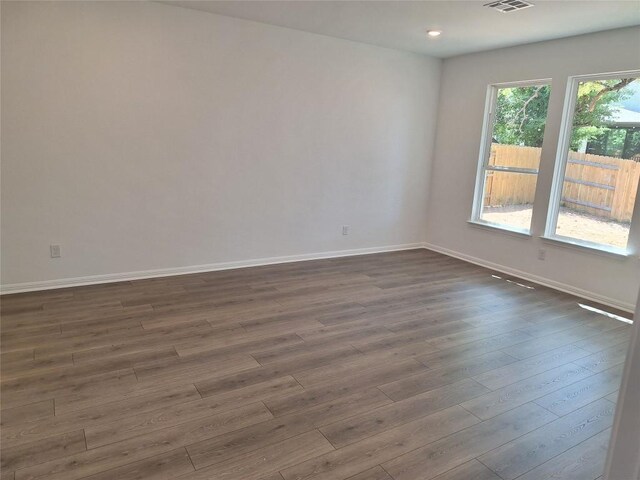 empty room with baseboards, dark wood finished floors, visible vents, and recessed lighting