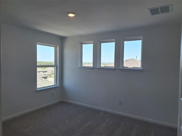 spare room with visible vents, baseboards, and dark carpet