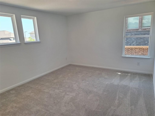 unfurnished room with carpet floors, a wealth of natural light, and baseboards