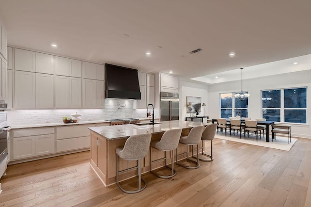10928 Seawall Dr, Austin, TX 78737 - kitchen featuring custom range hood, built in fridge, tasteful backsplash, recessed lighting, and an island with sink