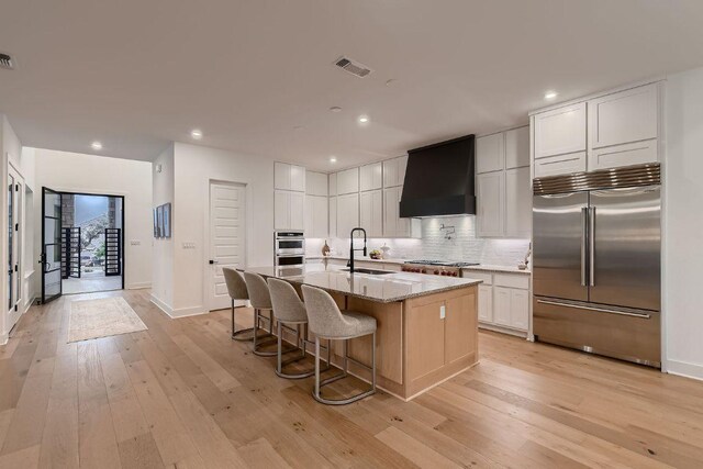 10928 Seawall Dr, Austin, TX 78737 - kitchen with stainless steel appliances, custom range hood, light wood finished floors, decorative backsplash, and recessed lighting