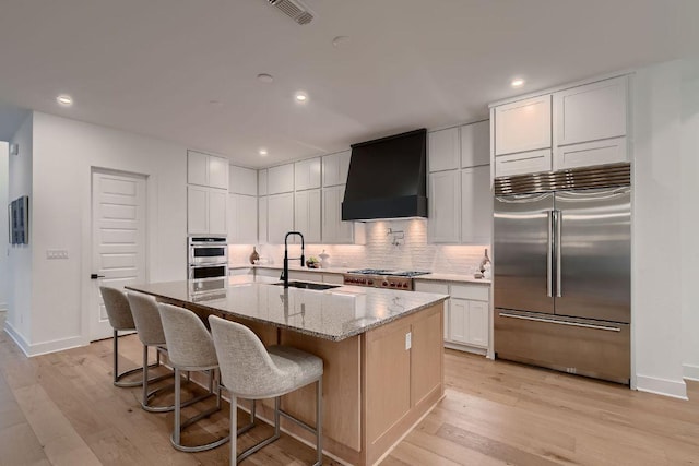 10928 Seawall Dr, Austin, TX 78737 - kitchen featuring stainless steel appliances, custom exhaust hood, light wood-style floors, decorative backsplash, and recessed lighting