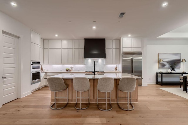10928 Seawall Dr, Austin, TX 78737 - kitchen with appliances with stainless steel finishes, wall chimney range hood, an island with sink, decorative backsplash, and recessed lighting