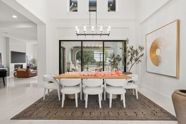 702 Serene Estates Dr, Austin, TX 78738 - dining space featuring a chandelier, a glass covered fireplace, a high ceiling, baseboards, and recessed lighting