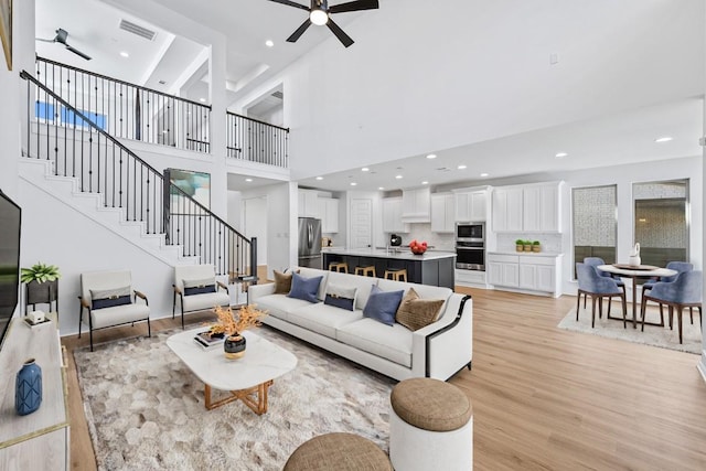 living room featuring light wood finished floors, visible vents, recessed lighting, a ceiling fan, and stairs
