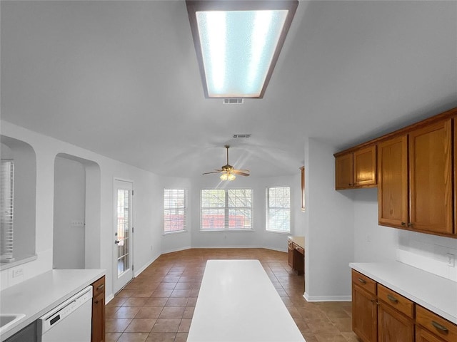 2804 Butler National Dr, Pflugerville, TX 78660 - kitchen featuring dishwasher, brown cabinets, light countertops, light tile patterned floors, and vaulted ceiling