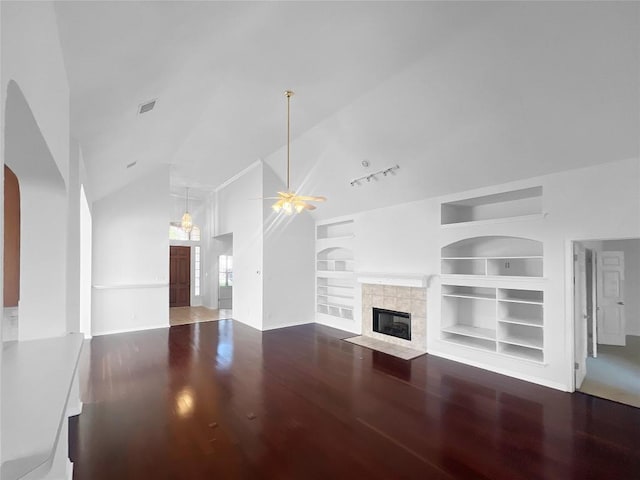 2804 Butler National Dr, Pflugerville, TX 78660 - unfurnished living room with lofted ceiling, wood finished floors, built in shelves, ceiling fan, and a tiled fireplace