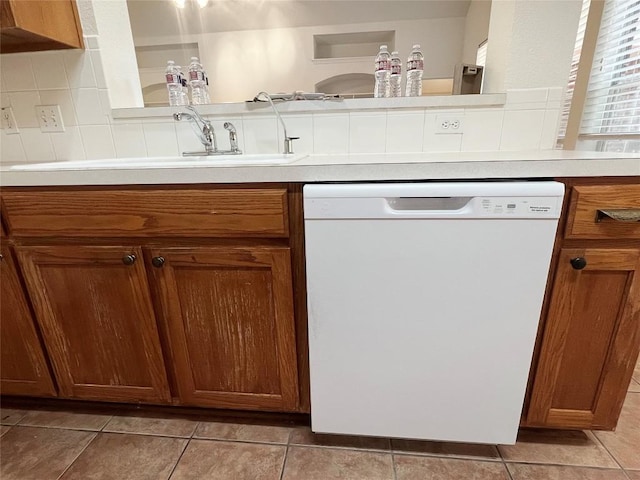 2804 Butler National Dr, Pflugerville, TX 78660 - kitchen with white dishwasher, a sink, brown cabinetry, light countertops, and light tile patterned flooring