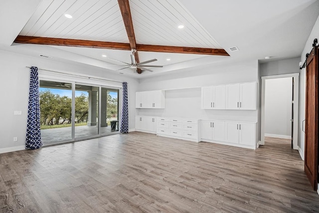 21603 Thomas Cv, Lago Vista, TX 78645 - unfurnished living room featuring a barn door, baseboards, beamed ceiling, light wood finished floors, and recessed lighting