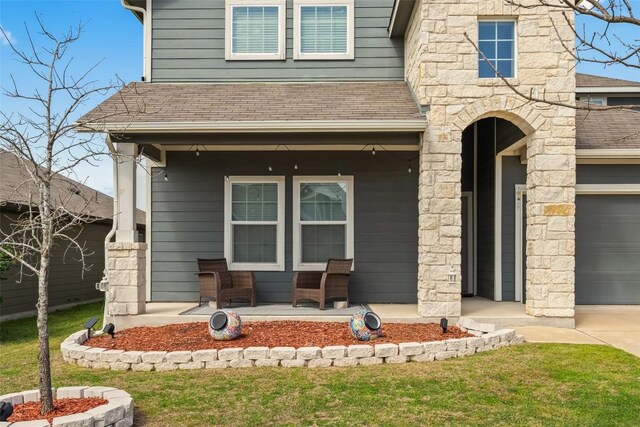 122 Denton Dr, Hutto, TX 78634 - doorway to property featuring stone siding, a porch, roof with shingles, concrete driveway, and an attached garage