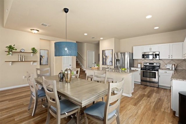 122 Denton Dr, Hutto, TX 78634 - dining room with light wood finished floors, visible vents, recessed lighting, and stairs