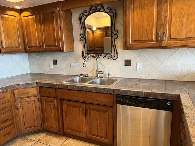 kitchen with stainless steel dishwasher, dark countertops, brown cabinetry, and a sink