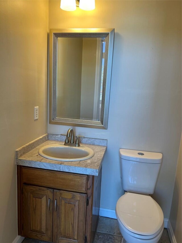 half bath featuring vanity, toilet, and baseboards