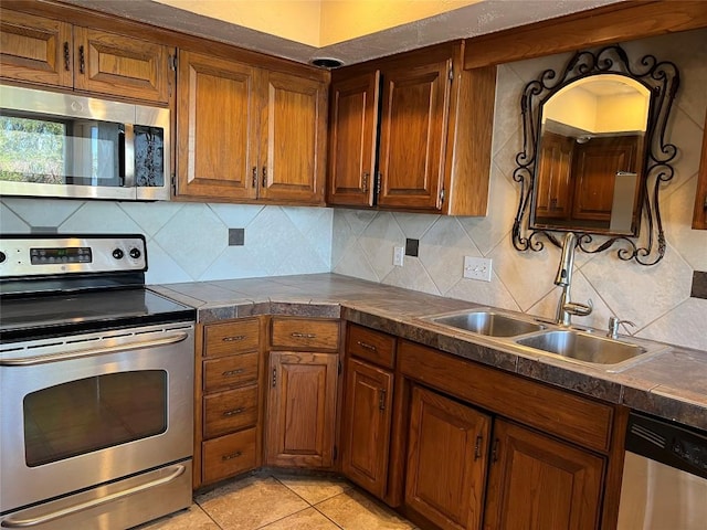 kitchen with brown cabinetry, backsplash, appliances with stainless steel finishes, and a sink