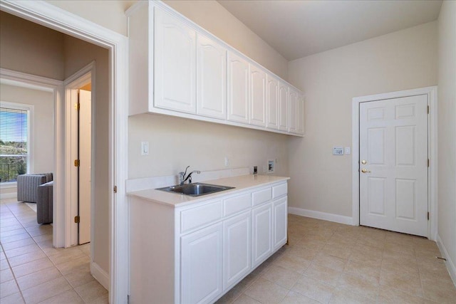 laundry area featuring baseboards, a sink, light tile patterned floors, and hookup for a washing machine