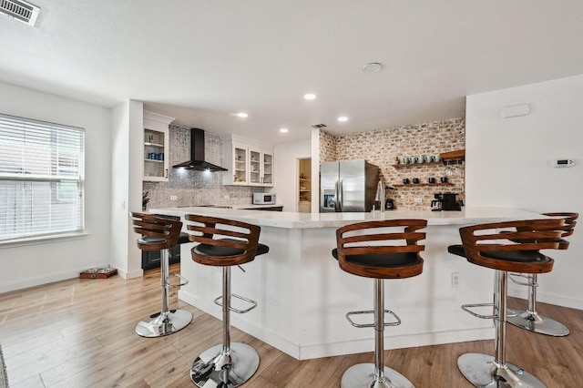 7004 Ashen Ln, Austin, TX 78747 - kitchen featuring wall chimney range hood, stainless steel fridge, decorative backsplash, light countertops, and recessed lighting