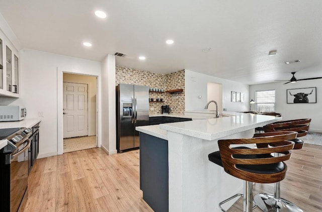 7004 Ashen Ln, Austin, TX 78747 - kitchen featuring appliances with stainless steel finishes, a breakfast bar, light wood-type flooring, a ceiling fan, and recessed lighting