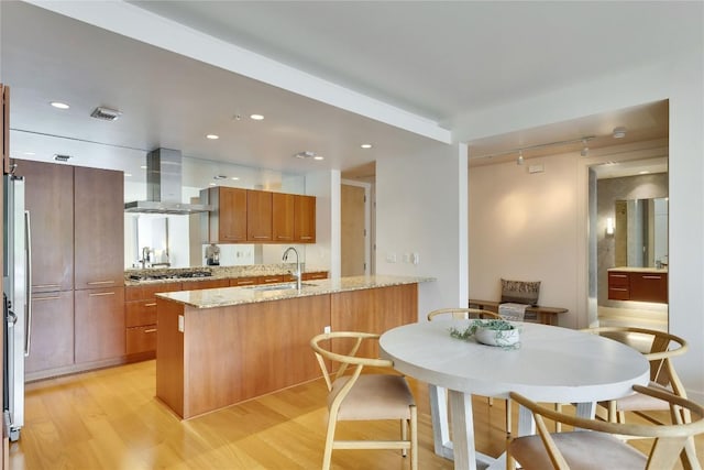 210 Lee Barton Dr Unit 308, Austin, TX 78704 - kitchen featuring brown cabinetry, rail lighting, a sink, ventilation hood, and light wood-style floors