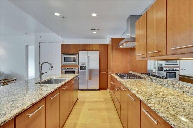 210 Lee Barton Dr Unit 308, Austin, TX 78704 - kitchen featuring a sink, brown cabinetry, wall chimney exhaust hood, stainless steel appliances, and visible vents