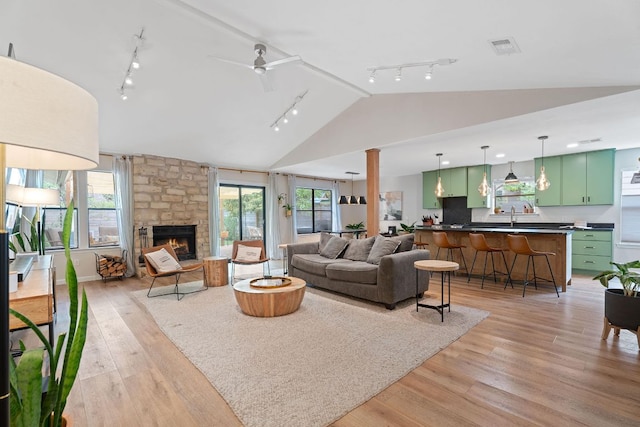9706 Woodshire Dr, Austin, TX 78748 - living room with track lighting, lofted ceiling, light wood-style floors, a fireplace, and ceiling fan