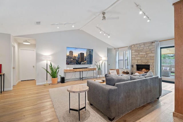 9706 Woodshire Dr, Austin, TX 78748 - living room featuring track lighting, vaulted ceiling, a ceiling fan, light wood finished floors, and a stone fireplace