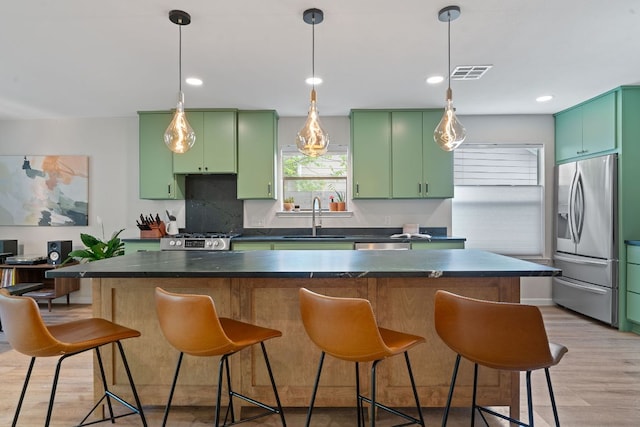 9706 Woodshire Dr, Austin, TX 78748 - kitchen with appliances with stainless steel finishes, green cabinetry, dark countertops, light wood-type flooring, and a breakfast bar area