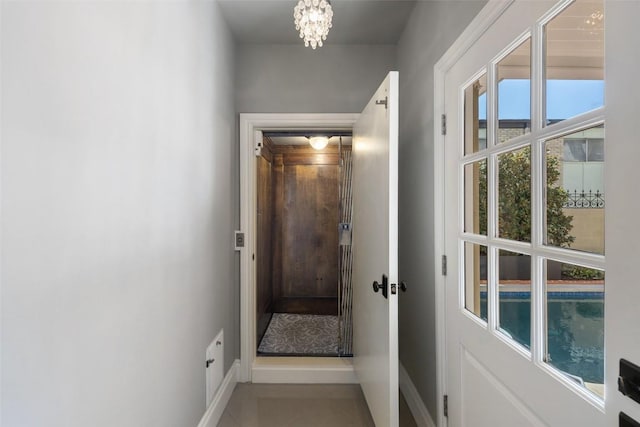 doorway with baseboards and a notable chandelier