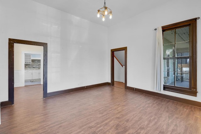 2705 E 2nd St, Austin, TX 78702 - spare room with wood finished floors, a chandelier, and baseboards