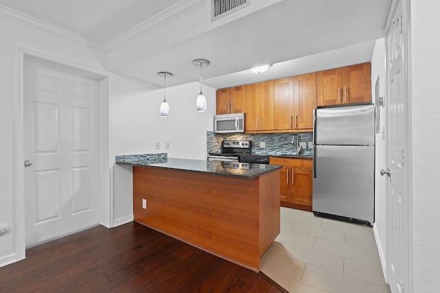 7685 Northcross Dr Unit 728, Austin, TX 78757 - kitchen featuring appliances with stainless steel finishes, brown cabinets, tasteful backsplash, a peninsula, and crown molding