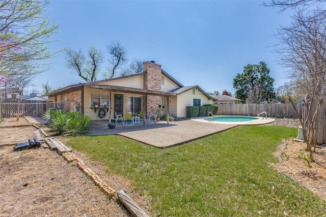 rear view of property with a lawn, a patio, a chimney, and a fenced backyard