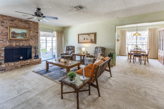 living room with visible vents, a ceiling fan, a fireplace, a textured ceiling, and light colored carpet