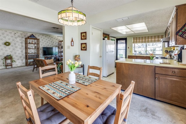 dining space with wallpapered walls, a textured ceiling, light carpet, and visible vents