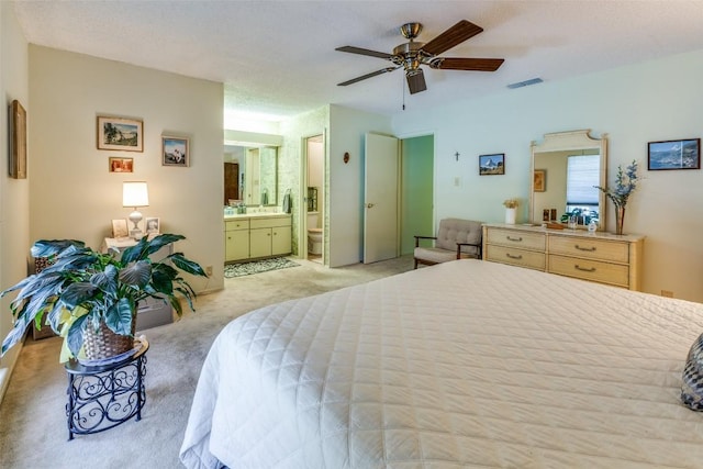 bedroom featuring ensuite bath, visible vents, a ceiling fan, and light carpet