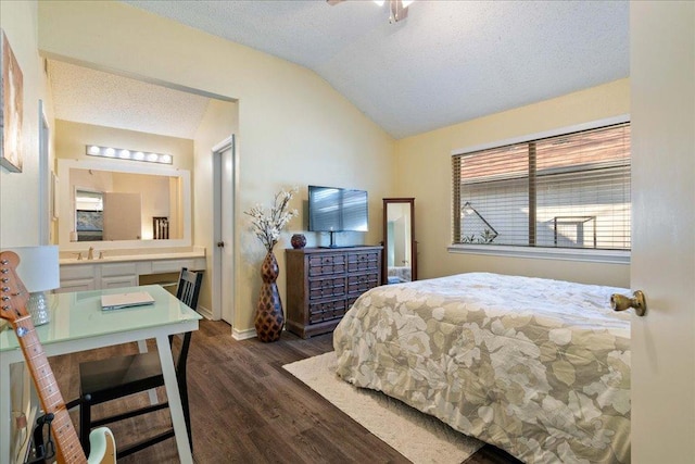 bedroom featuring vaulted ceiling, dark wood-type flooring, baseboards, a textured ceiling, and ensuite bath