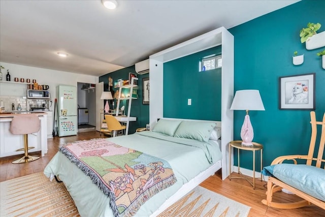 203 Ben Howell Dr, Austin, TX 78704 - bedroom featuring an AC wall unit, wood finished floors, freestanding refrigerator, and a closet