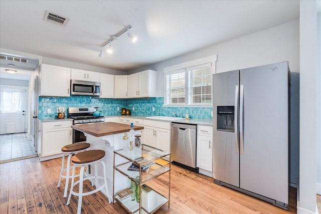 203 Ben Howell Dr, Austin, TX 78704 - kitchen featuring appliances with stainless steel finishes, wood counters, light wood-type flooring, white cabinetry, and healthy amount of natural light