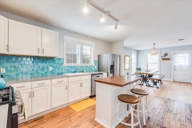 203 Ben Howell Dr, Austin, TX 78704 - kitchen featuring appliances with stainless steel finishes, light wood-style floors, butcher block countertops, rail lighting, and white cabinetry