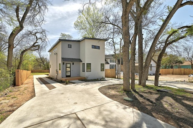 contemporary home featuring stucco siding, curved driveway, and fence