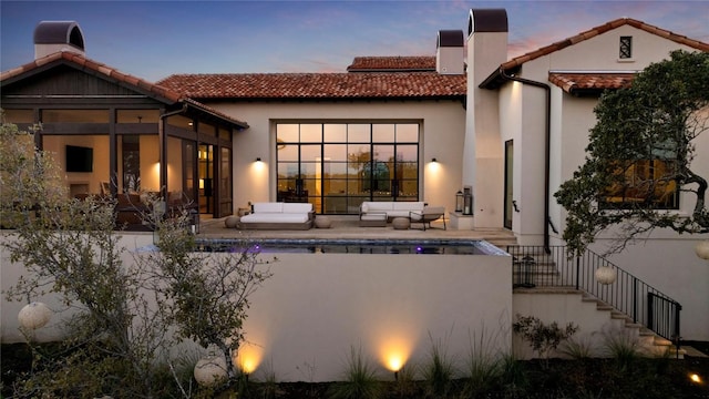 4401 Amarra Dr Unit 14, Austin, TX 78735 - back of house at dusk with an outdoor living space, a tiled roof, stairs, and an outdoor pool