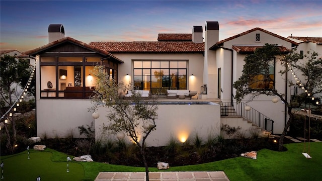 4401 Amarra Dr Unit 14, Austin, TX 78735 - back of property at dusk with a putting green, a chimney, a tiled roof, and outdoor lounge area