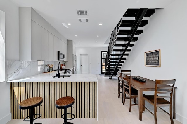 4703 Mount Vernon Dr Unit 2, Austin, TX 78745 - kitchen with stainless steel appliances, a sink, light wood-type flooring, light countertops, and a peninsula