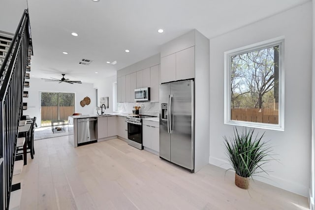 4703 Mount Vernon Dr Unit 2, Austin, TX 78745 - kitchen with appliances with stainless steel finishes, a peninsula, a sink, modern cabinets, and light wood-type flooring