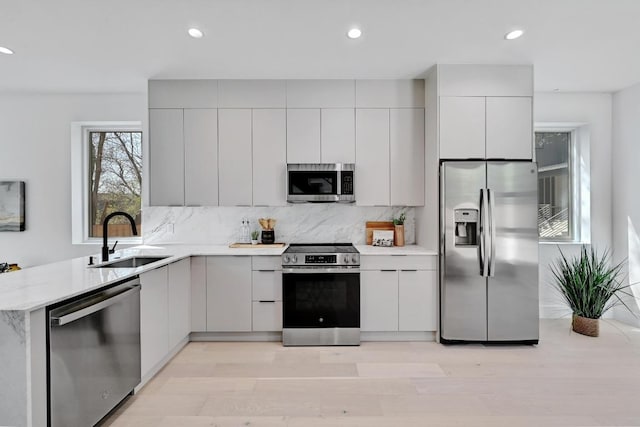 4703 Mount Vernon Dr Unit 2, Austin, TX 78745 - kitchen featuring stainless steel appliances, a sink, modern cabinets, light wood finished floors, and decorative backsplash